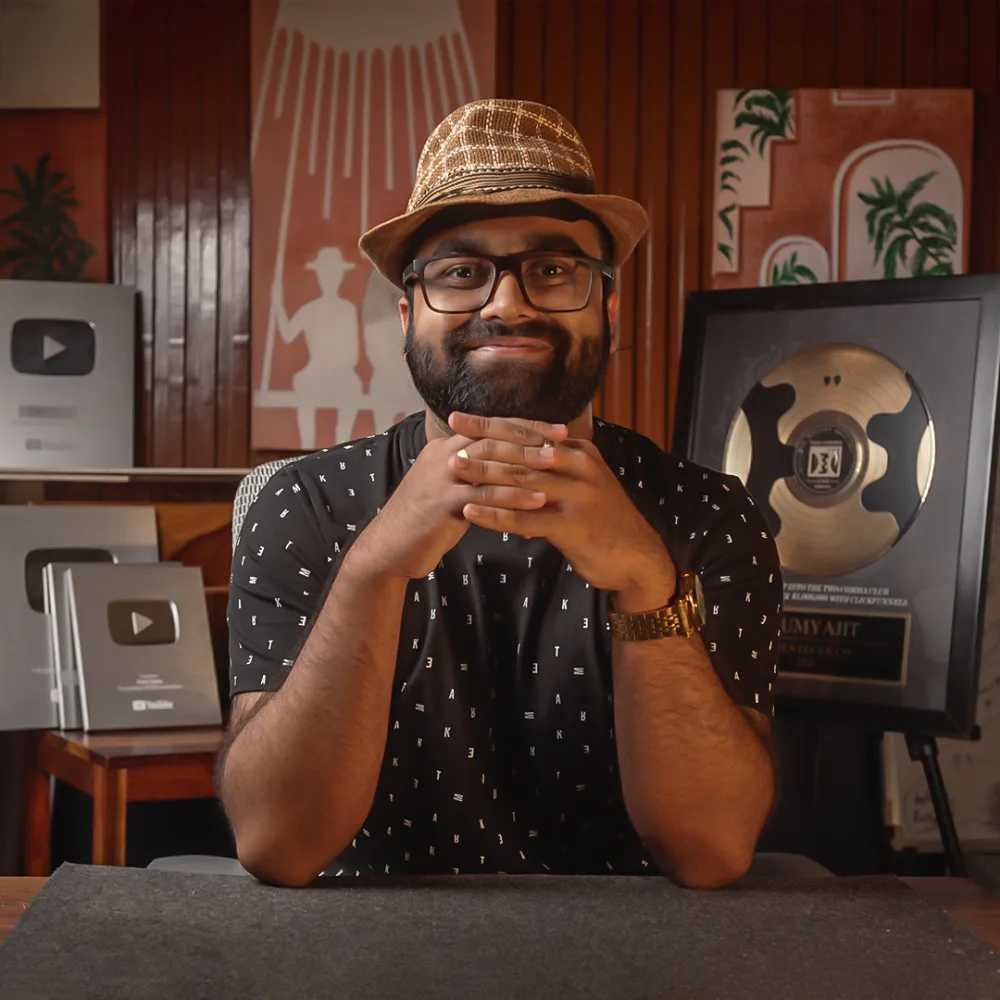 Samy, founder of Pixel Samy Studios, at his desk in front of his YouTube Creator Awards and Two Comma Club plaque
